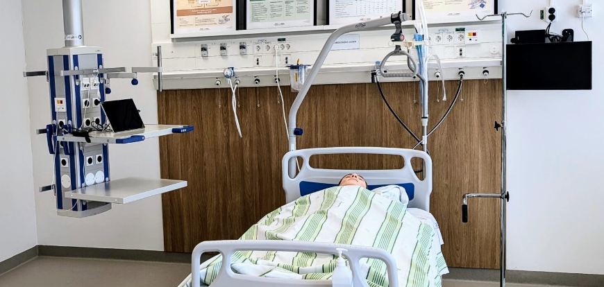 Bild från simuleringsmiljön på kursen "Sviktande vitalfunktioner". Docka som ligger i en sjukhussäng i sjukhusmiljö.